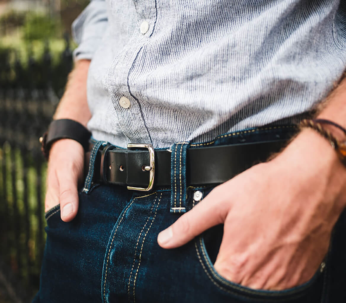 Man standing against fence with focus on his belt.